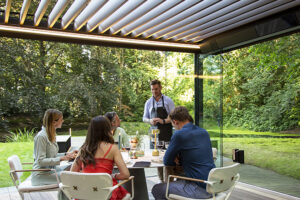 friends under a Renson Pergola outfitted with smart technology for shades and screens